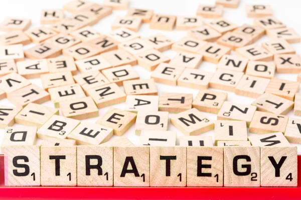 Scrabble letters spell out strategy with mixed up tiles in the background